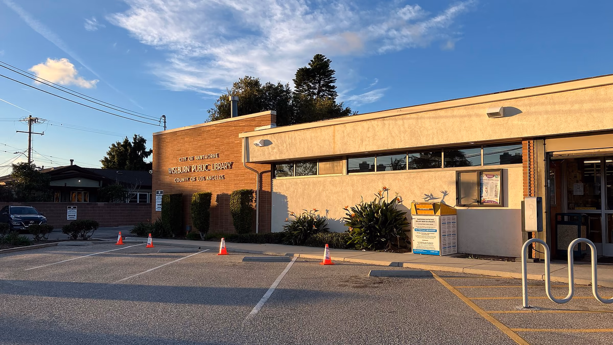 A low brick building in afternoon sun, under a blue sky with wispy clouds