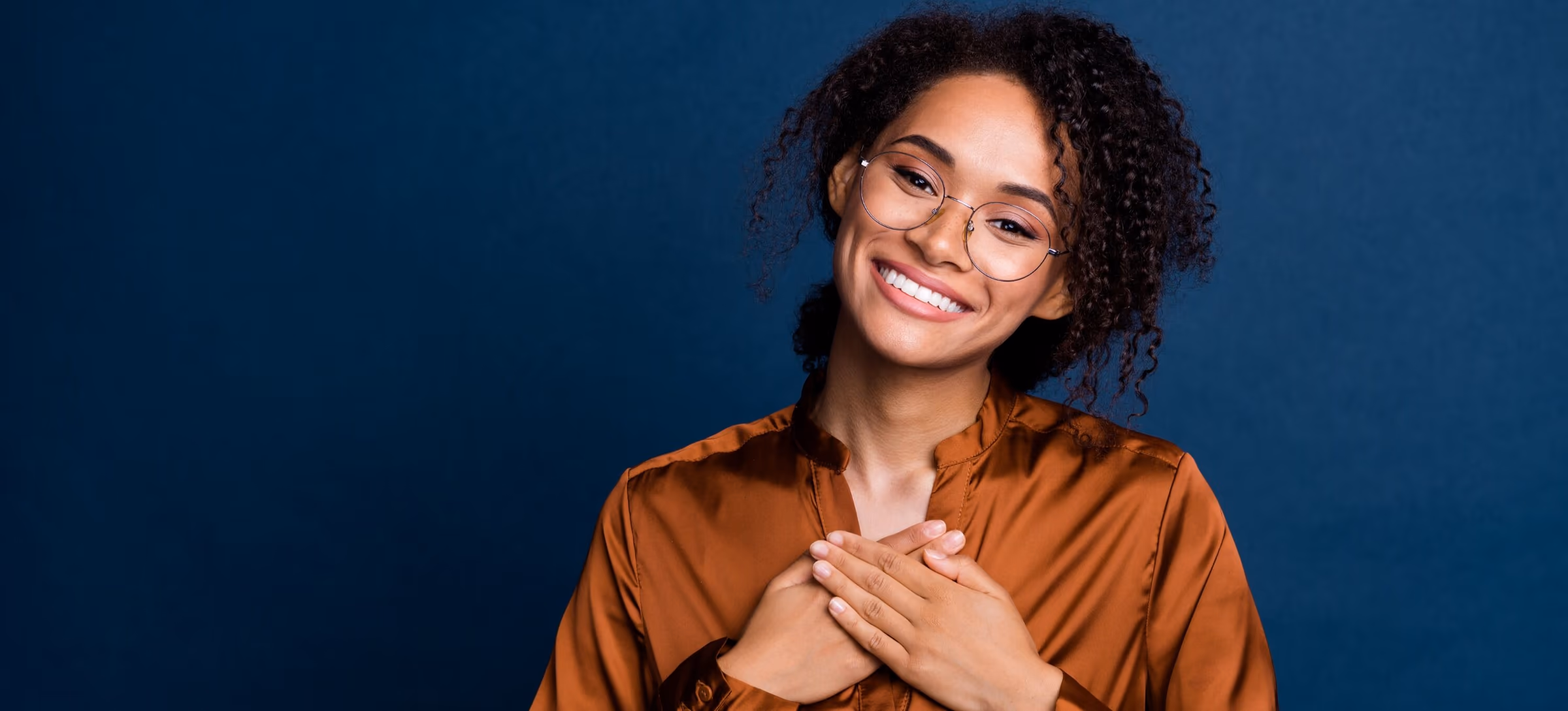 A smiling woman holding her hands over her heart