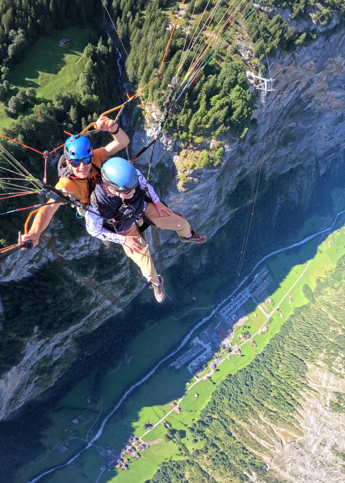 Dr. Peter Robbins tandem paragliding high above a mountain valley.